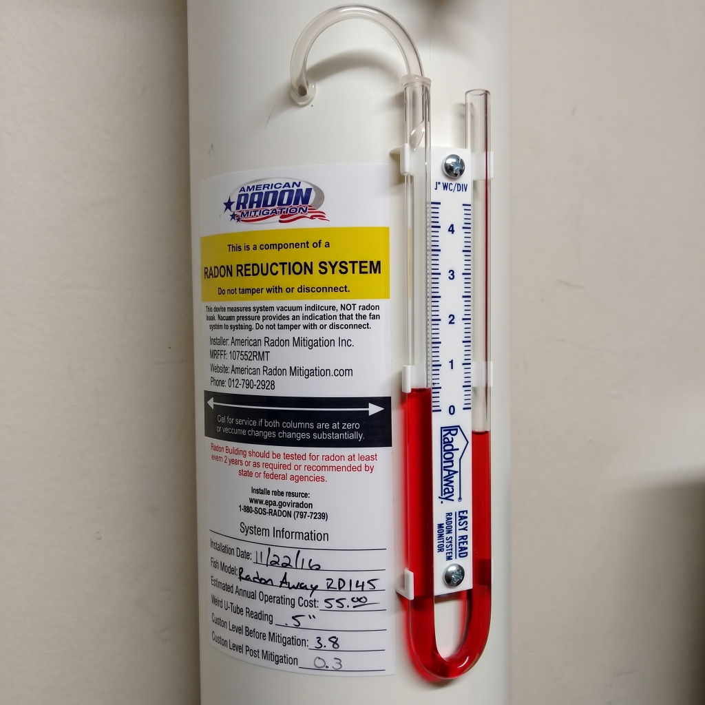 Radon system pressure gauge showing active suction (uneven liquid levels)