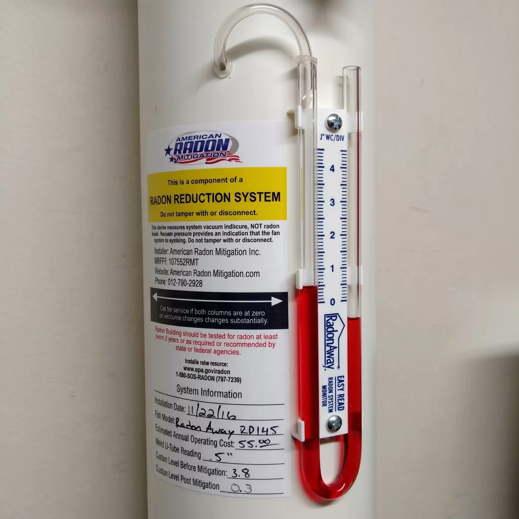Radon system pressure gauge showing active suction (uneven liquid levels)